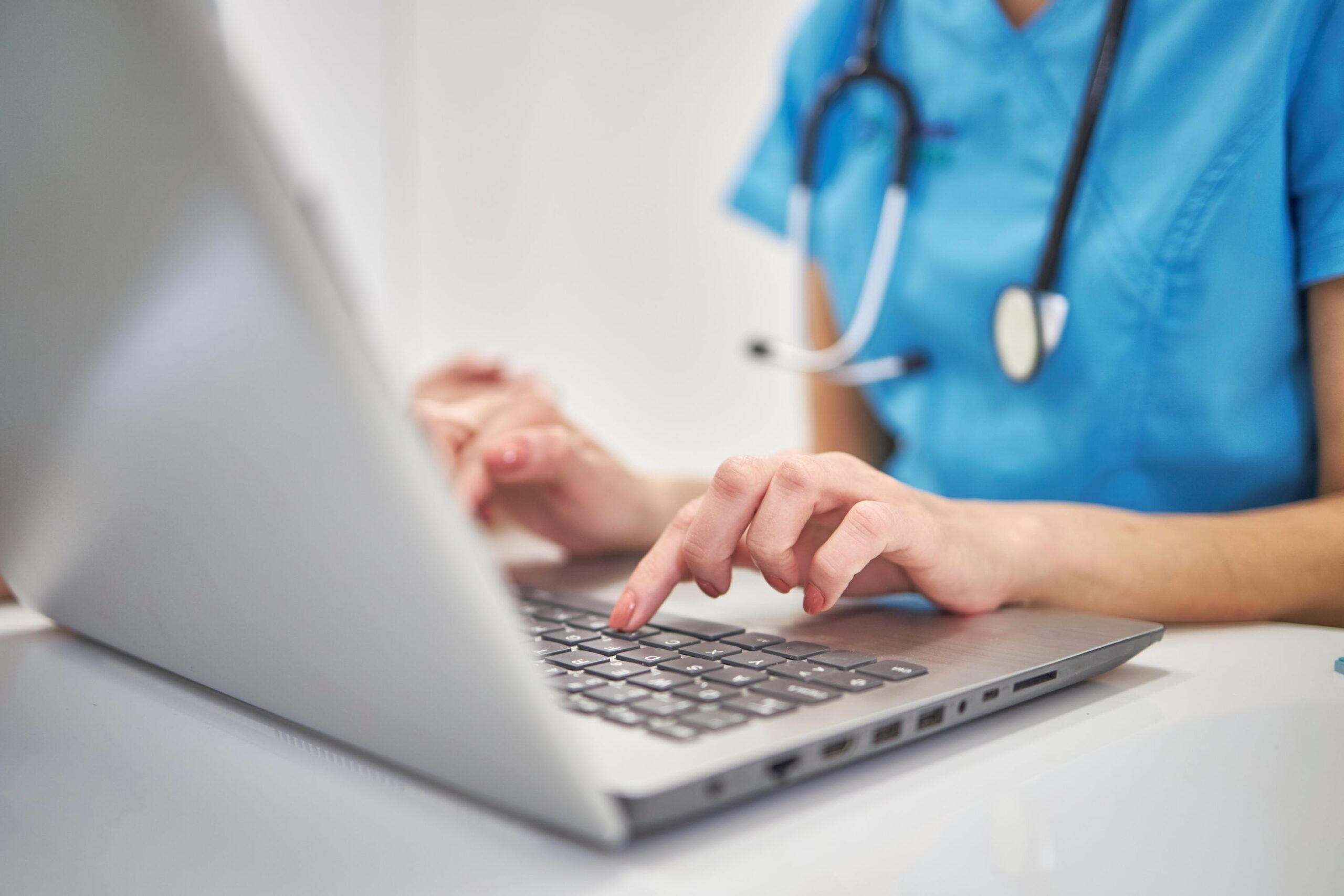 A photo of a nurse typing on the laptop